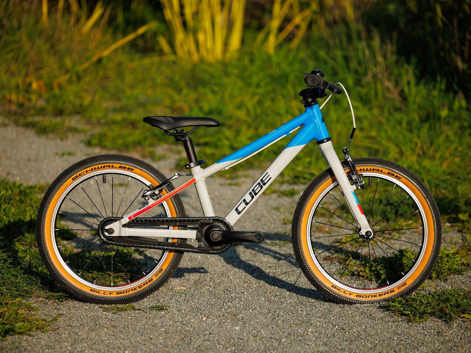 Ein silber, blaues Cube Kinderfahrrad steht auf einem Naturpfad.